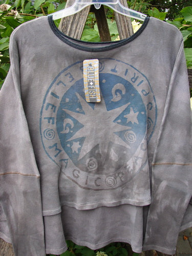 Barclay NWT Thermal Crop Top Belief Magic Mottled Spirit OSFA displayed outdoors, features a waffle-knit texture, scoop neck, varying hem, with a magical life-themed graphic and attached Blue Fish retail tag.