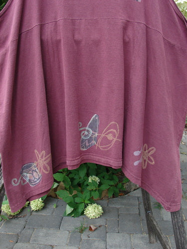 1994 Short Simple Smock Magic Music Beet Size 2 features a deep reddish-purple fabric with hand-painted floral and butterfly designs, hanging on a wooden rack, showcasing its unique sectional panels and varying hemline.