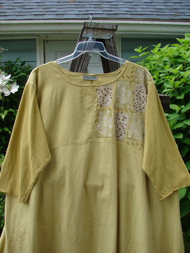 A mustard Barclay Cotton Sleeve Hemp Linen Sectional Dress with contrasting cotton sleeves and a cobblestone corner stone theme paint.