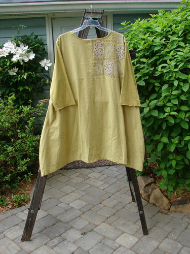 A mustard yellow dress with sectional upper and pleated A-line shape. Features contrasting cotton three-quarter length sleeves with a linen hemp bodice. Size 2.
