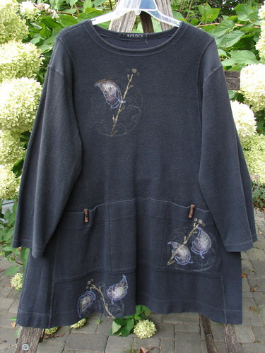 1998 Heavy Berber Kindlewood Tunic Leaf Sprig Black OSFA features a charcoal-gray knit with botanical prints, long sleeves, and toggle-accented pockets, photographed on a hanger amidst hydrangea blooms.
