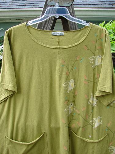 A Barclay Double Pocket Twinkle Top in Peapod, featuring a song bird theme paint. A green shirt with birds on it and lower exterior fun pockets.