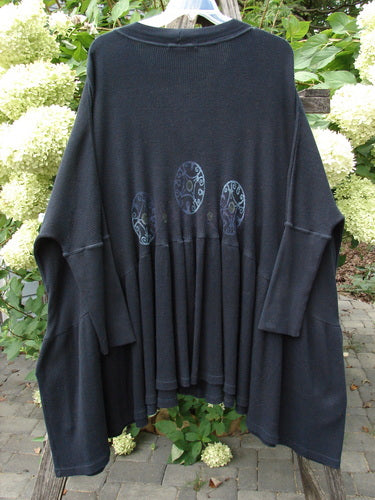 1997 Thermal Bungalow Jacket Celtic Medallion Cast Iron OSFA: A loose-fitting, dark cardigan with mandala motifs on the back, featuring colorful buttons, deep V-neck, oversized flounce, and gathered hem, hanging outdoors.