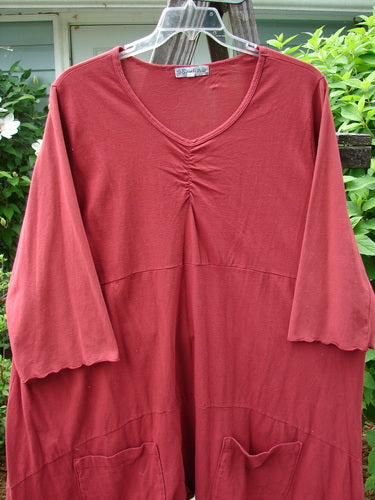 A red Barclay Gather Two Pocket Dress, made from medium weight organic cotton. Features include a sweet front gather, an A-line shape, and wide three-quarter length sleeves. Two exterior front drop pockets. Size 2.