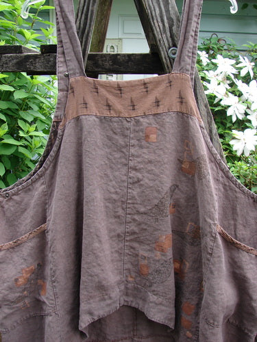 Barclay Linen Adjustable Snap Apron Jumper Playful Chirp Mocha Size 2, featuring adjustable shoulder and underarm snaps, dual side wrap pockets, and a playful birdie theme with varying hemlines.