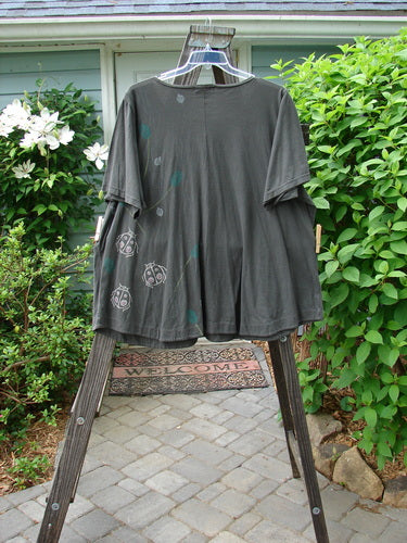 Barclay Double Pocket Twinkle Top Ladybug Grey Hunter on a swinger, showcasing a medium weight organic cotton t-shirt with ladybugs painted on it. Features include a ruffle hem, banded lower sleeves, and double drop pockets. A unique A-line shape and softly rounded neckline complete the design.