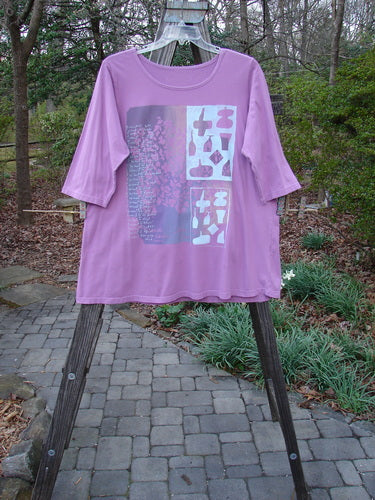 Barclay Three Quarter Sleeved Cafe Tee Want To Script Crocus Size 1 displayed on a rack, showcasing its rounded neckline, slight A-line shape, and three-quarter sleeves with script-themed design.