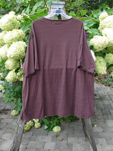 Barclay Art Tee Grid Flower Lower Lily Red Plum OSFA: Oversized brown top with drop shoulders and three-quarter sleeves, draped on a wooden support, featuring a rounded neckline and upward rounded front hem.