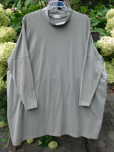 1999 Cotton Lycra Square Mock Pullover Unpainted Grey Stone Size 2: Oversized long-sleeve gray shirt with dolman drop shoulders and stand-up turtleneck, hanging on a clear hanger against a natural outdoor backdrop.