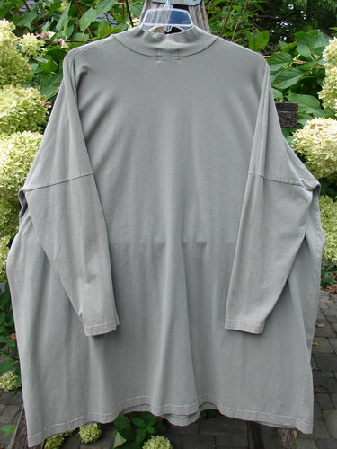 1999 Cotton Lycra Square Mock Pullover Unpainted Grey Stone Size 2, featuring an oversized boxy shape, dolman drop shoulders, and a mock turtleneck, hanging on a plastic hanger against leafy plants.