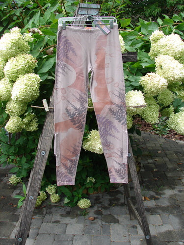 Barclay NWT Cotton Lycra Side Gather Drawcord Legging Forest Moon Oriel Size 1, featuring a muted earth-tone fern and circular pattern, hanging on a wooden ladder, showcasing its elastic waistband and tapered drawcord lowers.