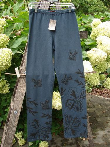 Barclay NWT Cotton Lycra Straight Pant Botanicals Lux Silhouette Size 1 displayed outdoors on a wooden ladder, featuring dark slate-blue fabric with black floral prints, showcasing a relaxed fit and full lower leg design.