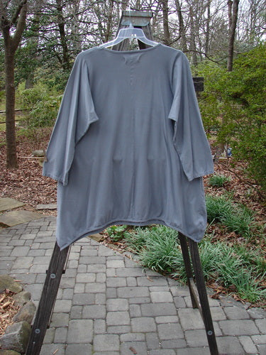 Barclay Long Sleeved Dip Side A Lined Tunic Daisy Logo Grey Storm Size 1 displayed on a clothing rack, showcasing its rounded ribbed neckline, three-quarter sleeves, and generous longer shape.