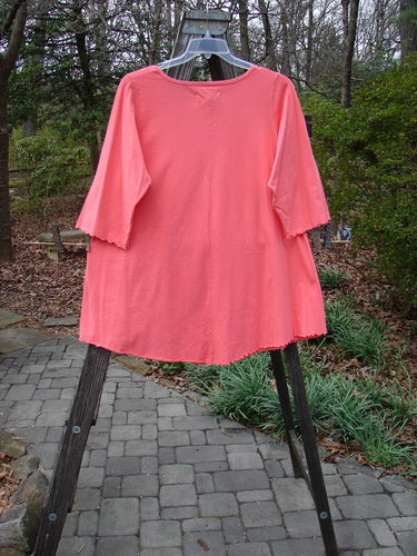 Barclay NWT Three Quarter Sleeved Cafe Pocket Top Fern Fall Geranium Size 1 on a rack, showcasing its feminine neckline, rounded side hemline, and double side entry kangaroo pocket.