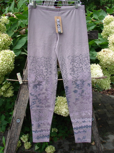 Barclay NWT Cotton Lycra Basic Legging Tiny Botanicals Sea Fog Size 1 displayed on a wooden rack, featuring a floral-geometric print on the lower legs, with a BLUEFISH tag clipped to the waistband.