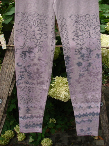 Barclay NWT Cotton Lycra Basic Legging Tiny Botanicals Sea Fog Size 1, featuring a paisley-and-floral motif in pale lavender, elegantly draped over a wooden ladder amidst white hydrangeas and greenery.