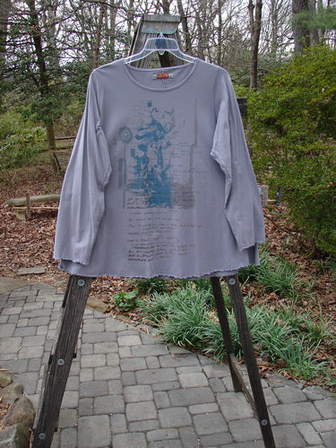 Barclay Long Sleeved Cafe Tee Story Script Grey Storm Size 1 displayed on a rack, showcasing its rounded neckline, swinging A-line shape, cozy long sleeves, and sweet curled edgings.