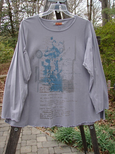 Barclay Long Sleeved Cafe Tee Story Script Grey Storm Size 1 displayed on a hanger, featuring a rounded neckline, long sleeves, and curled edgings, with visible blue writing on the front.