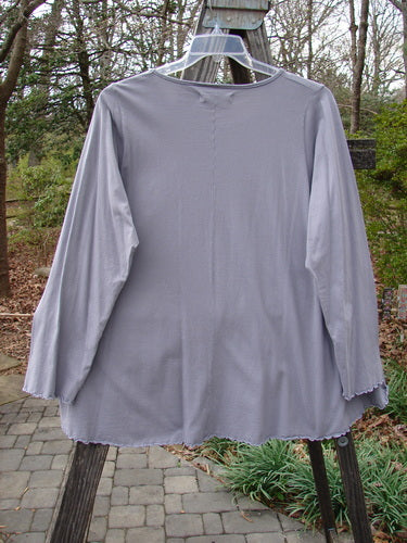 Barclay Long Sleeved Cafe Tee Story Script Grey Storm Size 1 displayed on a swinger, showcasing its rounded neckline, A-line shape, long cozy sleeves, and sweet curled edgings.