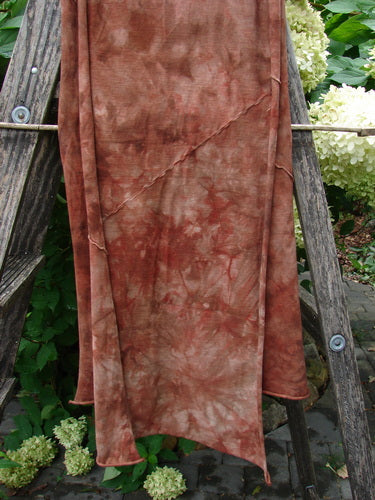 Barclay Diagonal Scarf Wrap Belief Spirit Magic Mottled Rust OSFA draped over a weathered wooden ladder, showcasing its raw curly edges and diagonal sectional seams in a delicate, organic cotton texture.