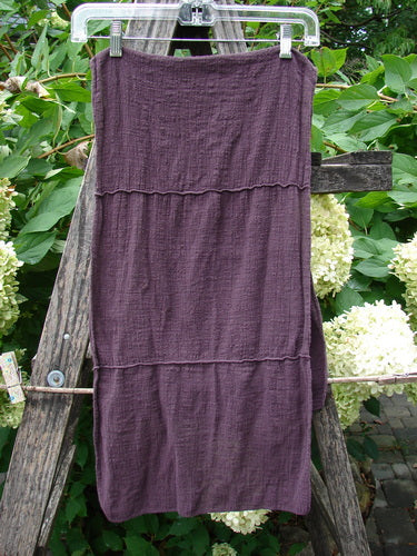 Barclay Gauze Sectional Scarf Wrap Unpainted Deep Burgundy OSFA, displayed on a clear hanger, features sweet finished edges and horizontal seams, crafted from lightweight cotton gauze, draped over a rustic wooden trellis.