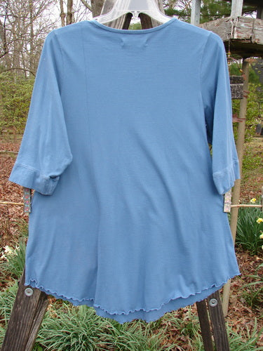 Barclay Banded Sleeve Twinkle Pocket Top Van Gogh Moon Peacock Size 1 displayed on a clothes rack, featuring a rounded neckline, double exterior pockets, three-quarter sleeves, and a rounded hemline.