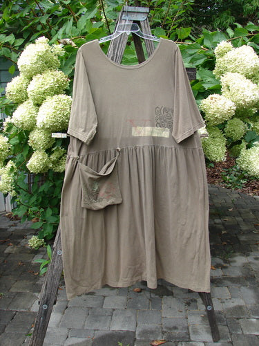 1994 Flower Garden Dress Wind Medallion Bark Size 2 showcased on a wooden ladder, highlighting its elbow-length sleeves, gathered waist, and removable pocket with buttons, set against a backdrop of hydrangeas.