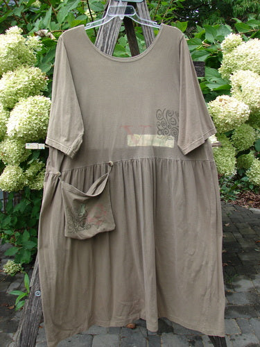 1994 Flower Garden Dress Wind Medallion Bark Size 2, featuring a loose-fitting, smock-style design with a scooped neckline, elbow-length sleeves, gathered waist, wide skirt, and removable pocket, hanging on a wooden ladder.