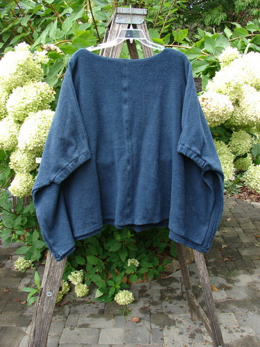 Barclay Celtic Moss Patched Poncho Single Six Daisy Ink Blue OSFA draped on a vintage ladder in a garden, highlighting its cozy, oversized fleece texture and open, versatile design.