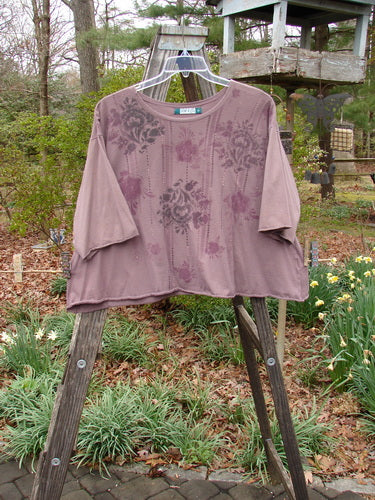 Barclay Three Quarter Sleeved Crop A Lined Tee Victorian Mottled Red Earth Size 2 displayed on a wooden rack, showcasing its A-line shape, rolled neckline, and curly edgings with a floral pattern.