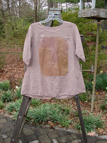 Barclay Linen Lucida Top Whisper Wheat Sprig Mauve Size 0 displayed on a hanger outdoors, showcasing its rounded neckline, flowy A-line shape, and almost three-quarter length sleeves.