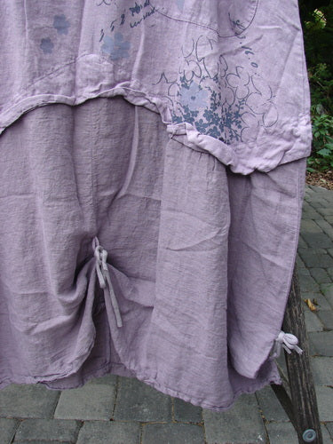 Barclay NWT Linen Explorer Jumper Tiny Botanical Sea Fog Size 0, featuring a loose fit with floral and abstract designs, adjustable gathers, and drawstring ties, draped over a chair outdoors.