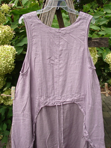 Barclay NWT Linen Explorer Jumper Tiny Botanical Sea Fog Size 0: A sleeveless, loose-fit linen smock with a scoop neckline, exterior upper pocket, and unique drawcord back, hanging outdoors against foliage.