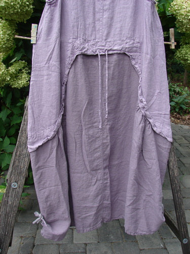 Barclay NWT Linen Explorer Jumper in Tiny Botanical Sea Fog, featuring a loose fit, drawstring waist, large side pockets, and a flowing, gathered A-line shape, hanging outdoors on a wooden frame.