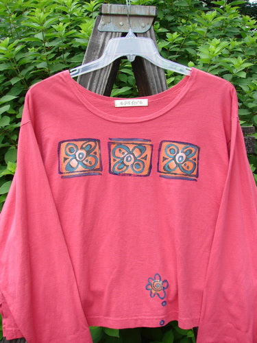 1997 Long Sleeved Crop Tee Tri Window Box Geranium Size 2: A pink shirt with a flower design on it. Wide crop shape, vented sides, drop shoulders, and a flattened wider neckline. Made from medium weight organic cotton.