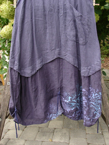 Barclay NWT Linen Explorer Jumper Botanical Blossom Purple River Mist Size 0, showcasing a high-low tiered design with a floral motif and adjustable drawstrings, draped outdoors with greenery.