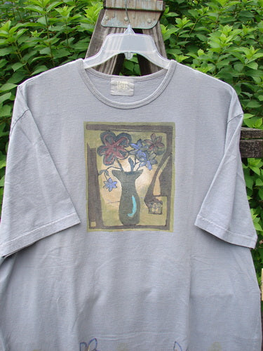 A faded lavender short-sleeved tee with a picture of five florals. Feminine rolled neckline, drop shoulders, and Blue Fish patch. Bust 56, waist 56, hips 56, length 32 inches. Size 2 from the 2000 Spring Collection.
