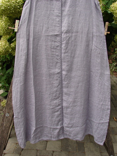 Barclay NWT Linen Sundress Garden Folly Amethyst Size 0 hanging outdoors on a clothesline, showcasing its medium-weight linen fabric and unique hemline, pinned by wooden clothespins against a greenery backdrop.