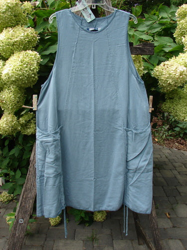 Barclay NWT Lyocell Joyous Jumper Unpainted Sea Green Size 0 features a sleeveless tunic-style with a round neckline, deep armholes, and side-seam pockets, displayed outdoors against lush garden foliage.