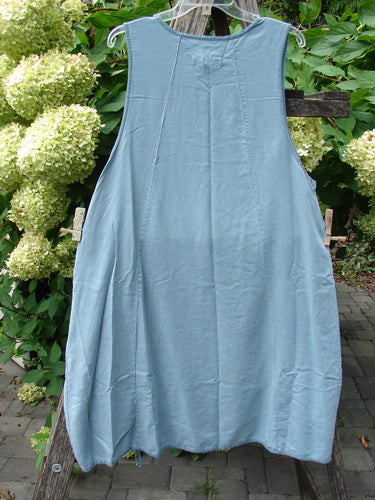 Barclay NWT Lyocell Joyous Jumper Unpainted Sea Green Size 0 features an A-line silhouette, deep arm openings, double drop pockets, and a drawcord hem, hanging outdoors against garden foliage.