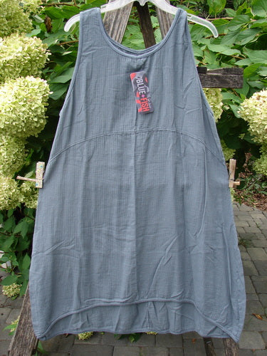 Barclay NWT Textured Salted Shift Unpainted Grey Diatom Size 0, featuring a loose-fitting, sleeveless A-line design with a rounded neckline and varying hemline, displayed on a hanger near green hydrangeas.