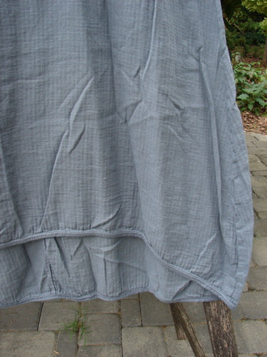 Barclay NWT Textured Salted Shift Unpainted Grey Diatom Size 0 hangs, showcasing its draped hem and lightweight, textured fabric, highlighting its unique design elements like the varying hemline and curved empire waist seam.