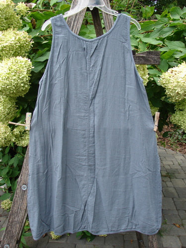 Barclay NWT Textured Salted Shift Unpainted Grey Diatom Size 0 hangs on a ladder, showcasing its loose A-line shape, rounded neckline, and empire waist seam against a backdrop of foliage and hydrangeas.