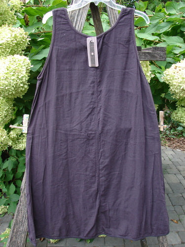 Barclay NWT Textured Salted Shift Unpainted Harrow Red Plum Size 0, sleeveless A-line dress with a rounded neckline and varying hemline, draped on a chair with hydrangeas in the background.