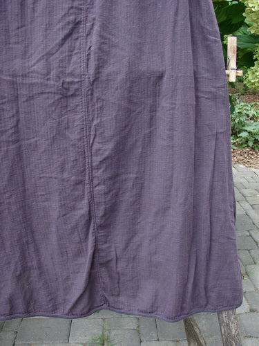 Barclay NWT Textured Salted Shift, Unpainted Harrow Red Plum Size 0, displayed draped over a wooden frame in an outdoor setting, showcasing its textured fabric and elegant hemline.