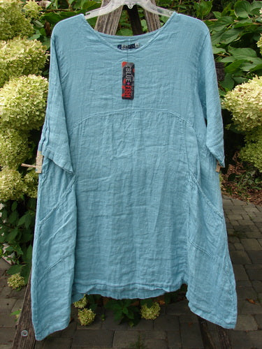 Barclay NWT Linen Zen Pocket Tunic Dress Unpainted Turquoise Size 0, features a loose fit, three-quarter sleeves, dual pockets, crinkled texture, rounded neckline, and varying hemline, suspended on a hanger.
