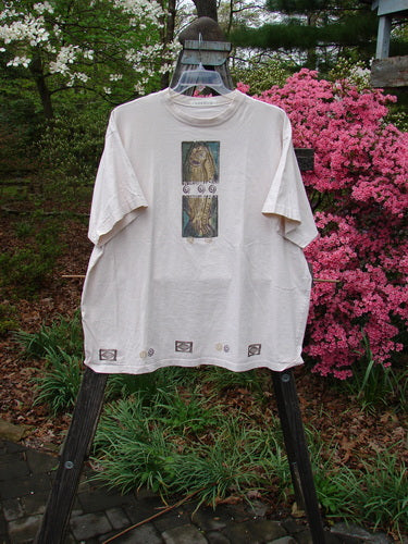 1996 Short Sleeved Tee Split Fish Birch Bark Size 2 displayed on a hanger outdoors, showcasing its drop shoulders, thicker ribbed neckline, and square boxy shape, adorned with a signature blue fish patch.