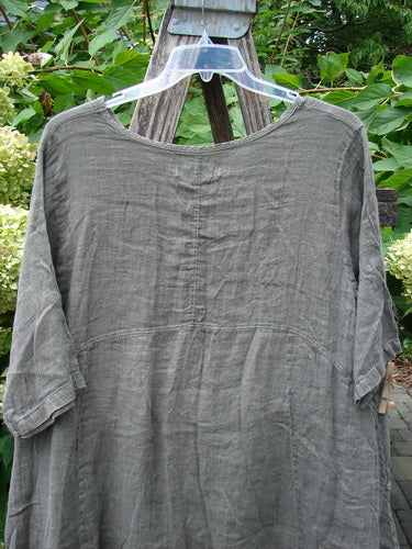 Barclay NWT Linen Zen Pocket Tunic Unpainted Stone Beach Size 0, featuring a loose fit, three-quarter sleeves, dual pockets, and an A-line shape, displayed outdoors with hydrangea blooms in the background.
