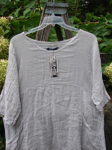 Barclay NWT Linen Zen Pocket Tunic Unpainted Pearl Smoke Size 0 displayed on a hanger showcases a loose-fitting, A-line design with three-quarter sleeves, dual drop pockets, and a varying hemline.