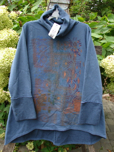Barclay NWT Fleece Cowl Neck Sweatshirt Metallic Daisy Vintage Indigo Size 0 displayed outdoors, showcasing its cowl neck, tunic length, and subtle geometric print in rusty orange and blue on slate-blue fabric.